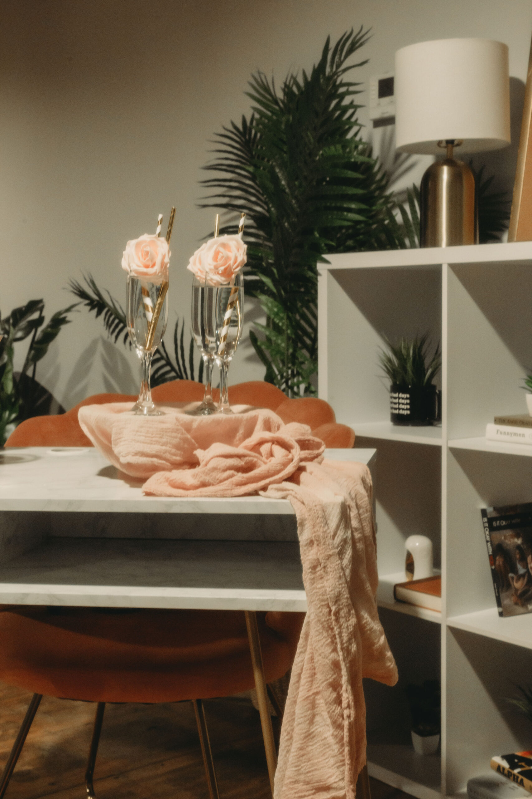 Pretty custom bar setup with champagne and pink rose garnishes and gold striped straws on a platter draped in a peach colored scarf, setup by On the Rocks Mobile Bartending Co in Milwaukee, WI