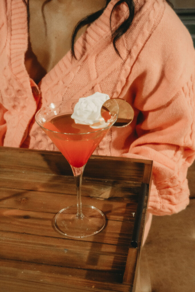 branding shoot for Milwaukee business On the Rocks Mobile Bartending Company, closeup of a wooden tray with a pink cosmo with a round gold branded drink topper with their logo on the rim and a white rose in the glass