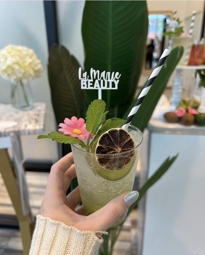 a clear refreshing mojito drink with a black and white striped paper straw, fresh mint garnish and a small pink flower