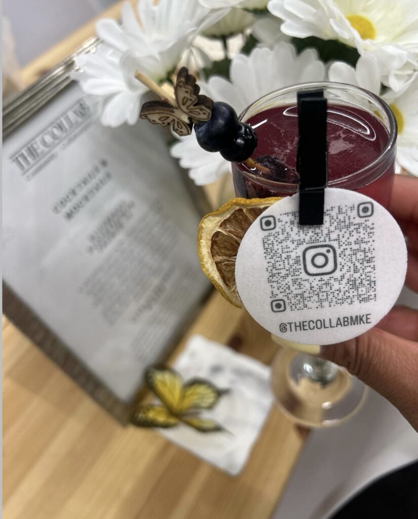 Gorgeous fresh Blueberry Elderflower French 75 cocktail with dried fruit garnish pinned to rim and wooden butterfly stir stick with fresh blueberries created for a bar setup by On The Rocks Mobile Bartending for a Milwaukee women in business networking event