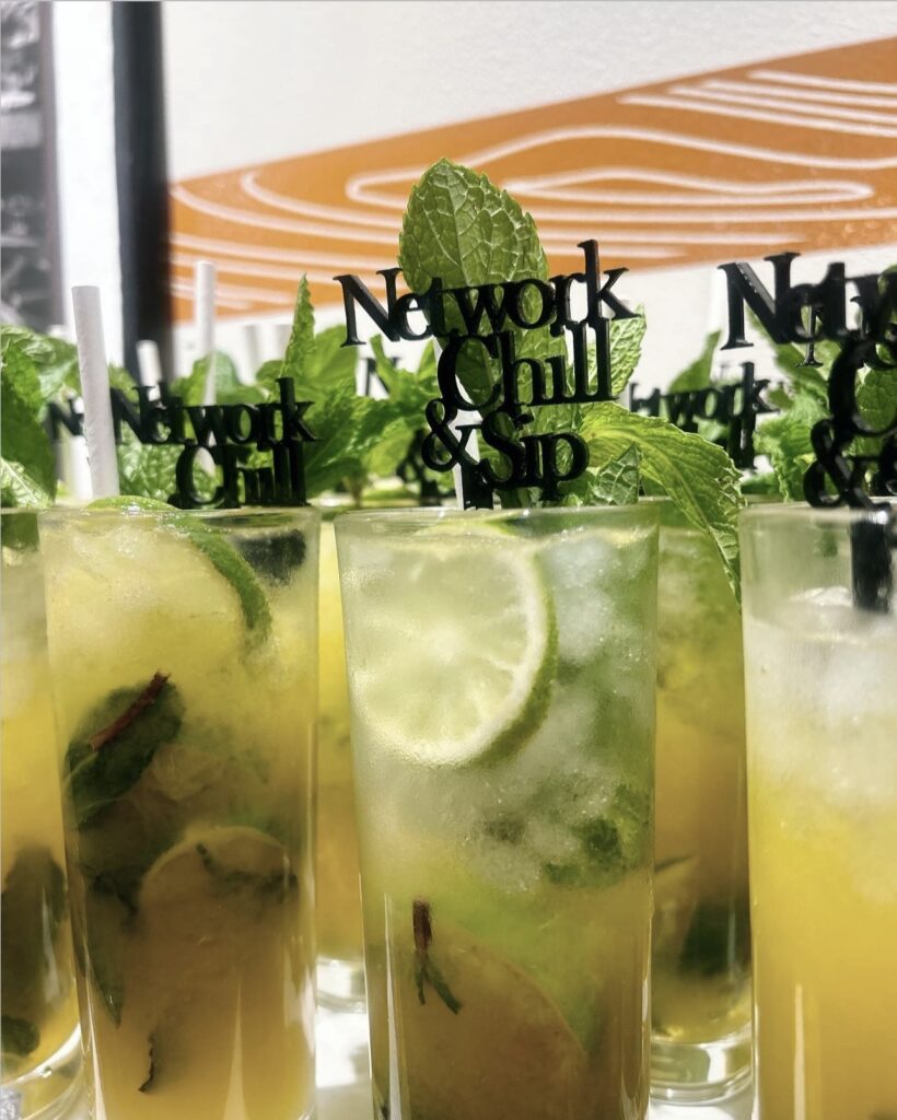 Bar display of Craft Orange, Mango, Passionfruit Mojitos and Mocktail Mojitos with fresh fruit and mint garnishes and a stir stick with the event name lined up for private networking event in Milwaukee, WI